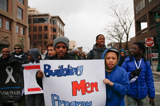 Students from H. W. Smith Middle School hold up a sign at the march. They are part of a group that call themselves the MOST Club, or Men of Strength.